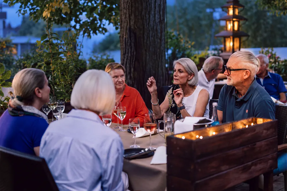 Gäste genießen einen Abend auf der beleuchteten Terrasse